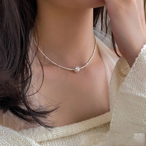 Detailed close-up of a single white pearl on a delicate silver chain necklace on neck