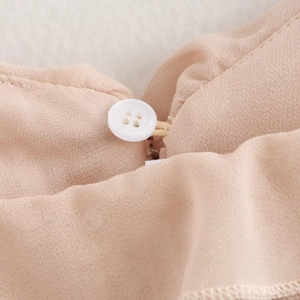 Close-up of ruffled sequin camisole top featuring a white button and soft fabric texture
