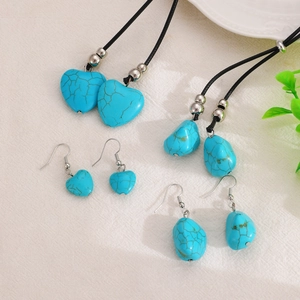 Flat lay of vintage turquoise jewelry sets with heart and teardrop pendants on linen