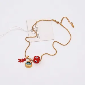 Gold chain necklace with evil eye pendants and red coral charm on white background