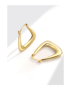 Macro shot of geometric triangular gold earrings with a smooth polished mirror finish
