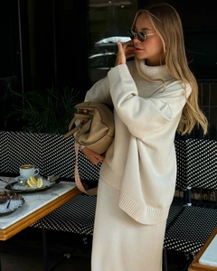 Détail d'un ensemble en maille beige avec pull à col roulé et jupe longue coupe décontractée