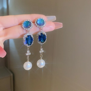 Détail de boucles d'oreilles pendantes argentées avec gemmes bleues et perles