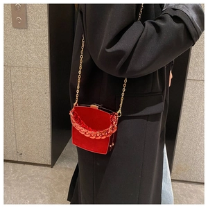 Close-up of a red hardshell box bag with chunky chain strap on a black coat model