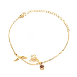 Macro shot of gold tulip charm bracelet with a red birthstone and adjustable lobster clasp