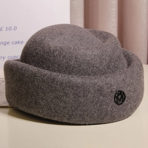 Close-up of wool felt hat with vintage silver M metal badge and elegant rolled edge