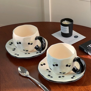 Detail of white ceramic coffee set featuring hand-painted black cherry patterns and wavy edges