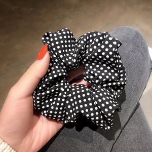 Detail of a black and white polka dot scrunchie made of soft chiffon fabric