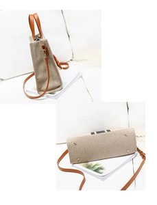 Detail of canvas bag with brown leather handles and protective metal studs on the bottom