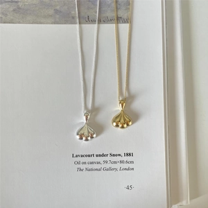 Artistic detail of gold and silver teardrop pendants on a white aesthetic background