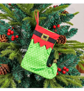 Close-up of green polka dot Christmas stocking with belt hanging on festive tree branches