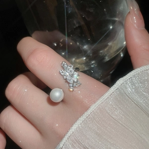 Macro detail of adjustable ring with white pearl and sparkling zircon bow decoration
