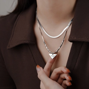 Detail of silver double layer chain necklace with a triangle pendant engraved with PARIS