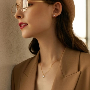 Close-up of minimalist gold heart jewelry set including earrings and necklace on model