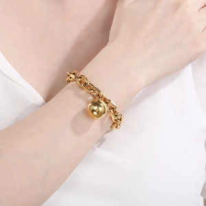 Detail of chunky gold chain bracelet with a large polished ball pendant on model