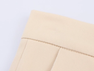 Detailed close-up of premium beige suit fabric showing precise stitching and canvas texture