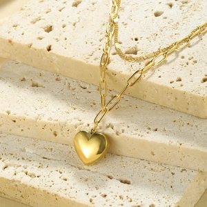 Detail of gold double-layer necklace with paperclip chain and solid heart pendant