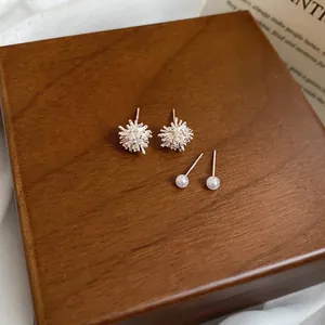 Fireworks zircon and pearl stud earrings set displayed on a vintage wooden box and white silk