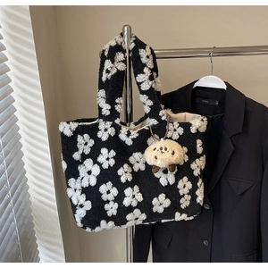 Close-up of plush floral tote bag with lamb wool texture and cute bear pendant on a rack