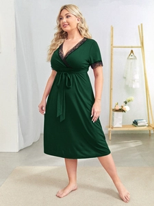 Detail of dark green plus size V-neck dress with black lace trim and adjustable waist belt