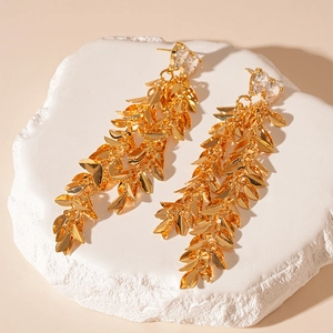 Detailed macro view of golden leaf tassel earrings with sparkling zircon gemstones