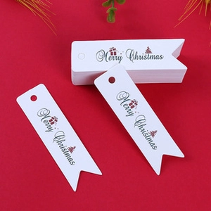 Close-up of white swallowtail paper tags with Merry Christmas print and holiday motifs