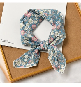 Detail of blue cotton linen scarf with pink daisy patterns on a decorative book