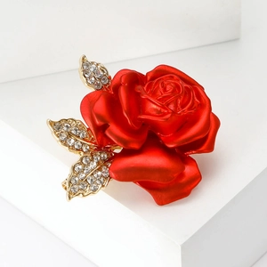 Detailed view of red rose brooch with golden leaves and sparkling crystal rhinestones
