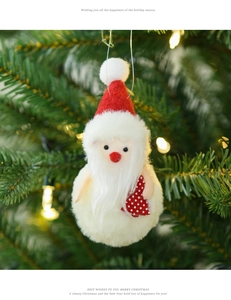 Detail of plush Santa ornament with white fluffy body and red hat on Christmas tree