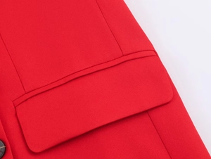 Macro detail of a red double-breasted blazer showing pocket stitching and twill texture