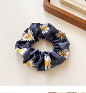 Detailed shot of dark blue satin daisy scrunchie on a clean minimalist background