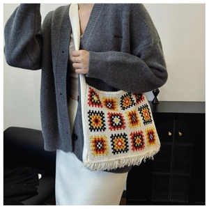 Detail of knit shoulder bag featuring colorful square patterns and tassel fringe finish