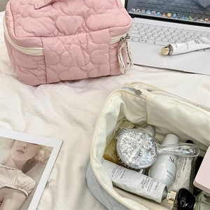 Quilted makeup bag set with zipper and ribbon puller on cozy home bedding background