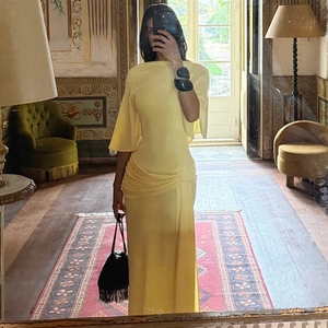 Detail of elegant yellow maxi dress showing soft draped fabric and pleated texture