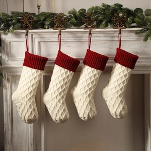 Set mit vier cremefarbenen Zopfmuster-Weihnachtssocken mit rotem Rand am Kamin