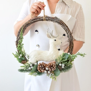 Nordic Christmas wreath with pine cones and white reindeer figurine held by a model