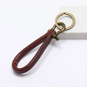 Macro detail of brown leather keychain with vintage bronze D-ring shackle and keyring