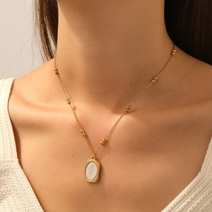 Vintage gold bead necklace with embossed floral oval pendant on model's neck