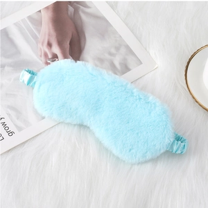 Detailed view of plush blue sleep mask with elastic strap on soft cozy white rug