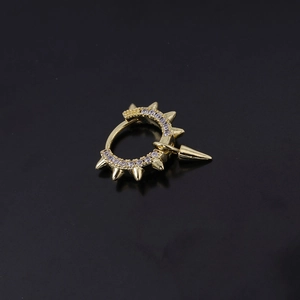 Pendiente punk dorado con circonitas y colgante de punta cónica sobre fondo negro