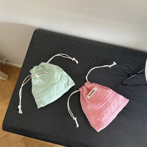Detail of mint green and pale pink drawstring storage bags with soft bubble fabric texture