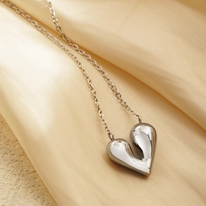 Polished silver irregular heart pendant necklace on champagne silk background