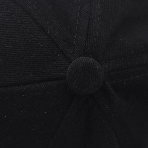 Macro detail of the top button and six-panel stitching on the black cotton baseball cap