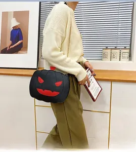 Detail of pumpkin-shaped crossbody bag with red demon face and gold chain strap