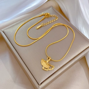 Detail of golden ginkgo leaf pendant necklace on soft silk background