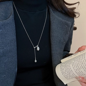Elegant Y-shaped necklace with baroque pearl and silver pea pendant on black turtleneck