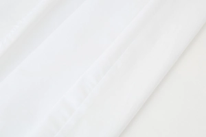Detailed close-up of white dress fabric showing fine weaving texture and neat stitching