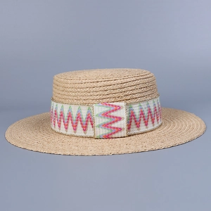 Close-up of beige raffia sun hat featuring a colorful geometric patterned ribbon and gold trim