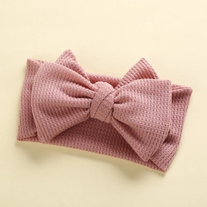 Close-up of pink waffle knit baby headband with a large handmade decorative bow