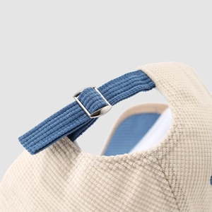 Close-up of corduroy baseball cap back with adjustable metal buckle and blue strap